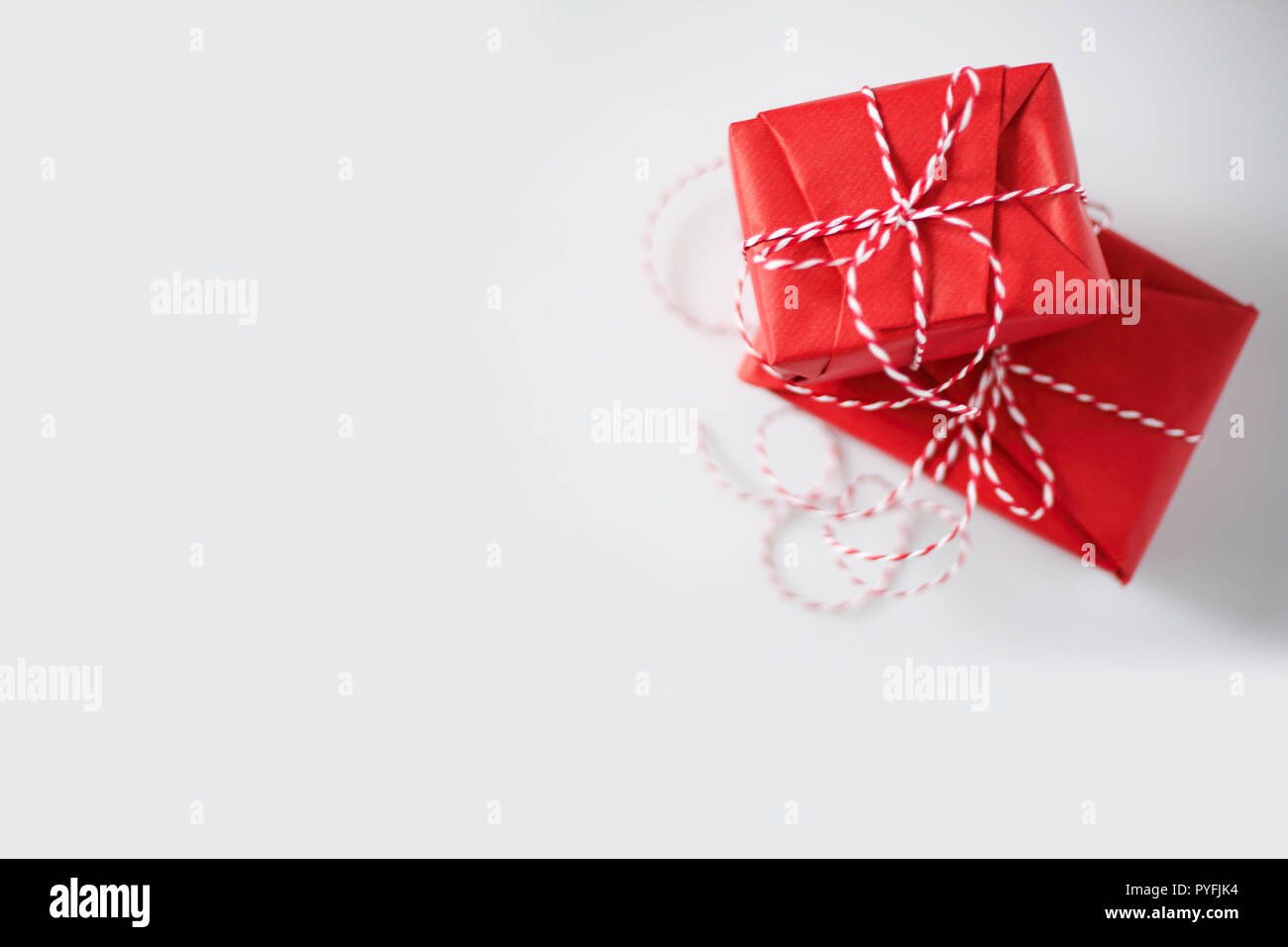 Christmas gift boxes wrapped in red paper and bow of dtriped rope on ...