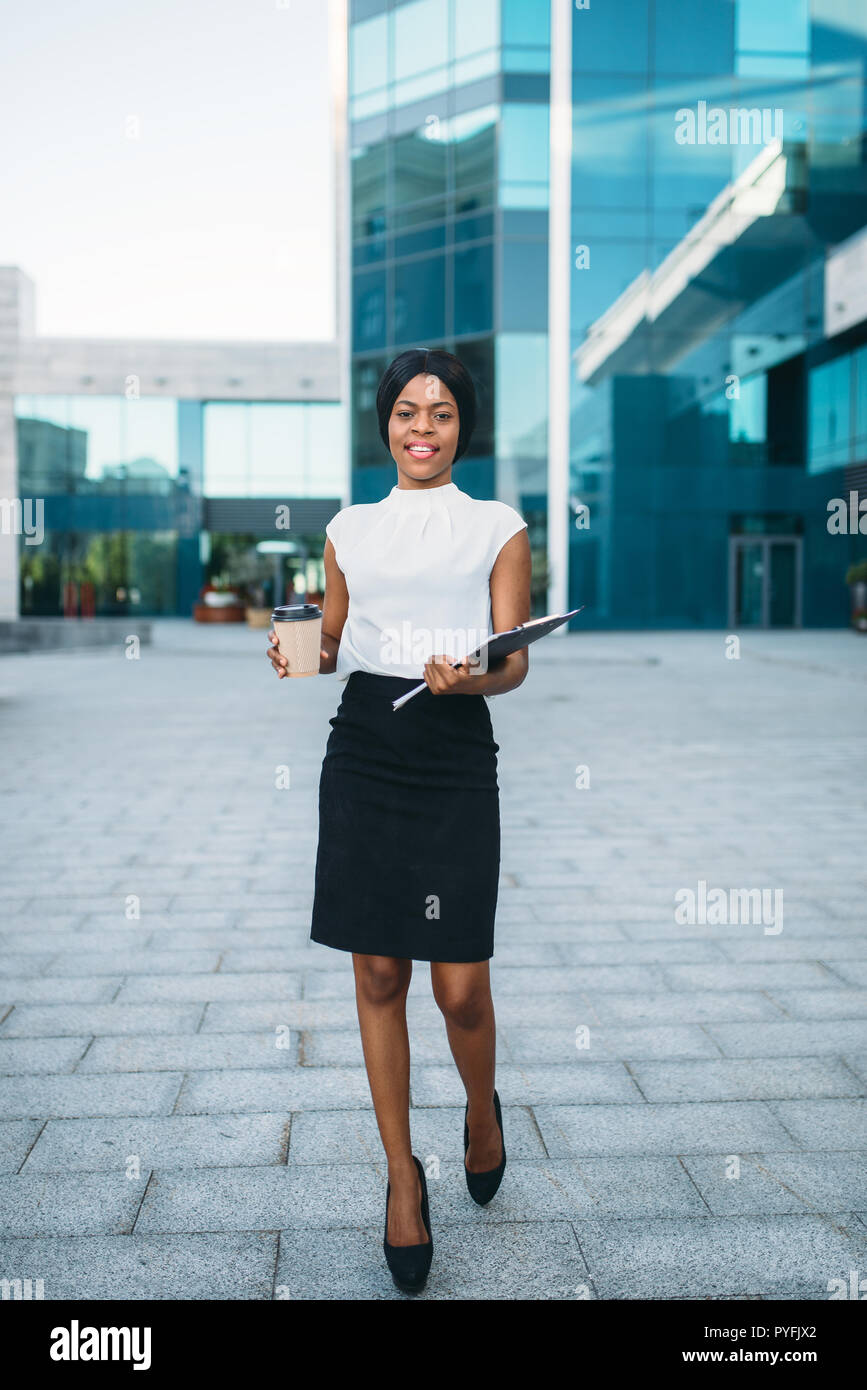 Business woman with cardboard coffee cup and notepad outdoors