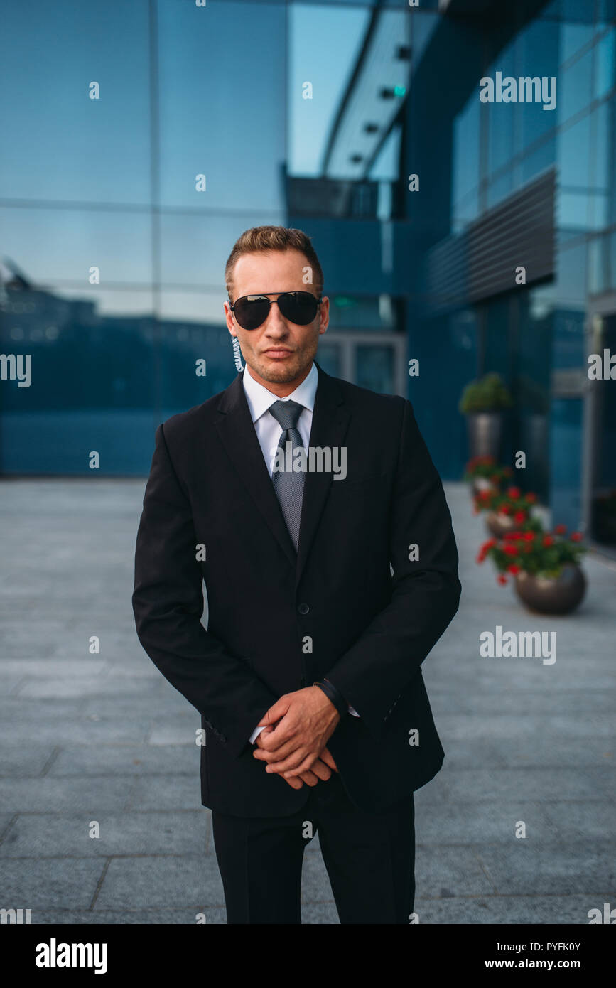 Male bodyguard in suit and sunglasses outdoors. Guarding is a risky