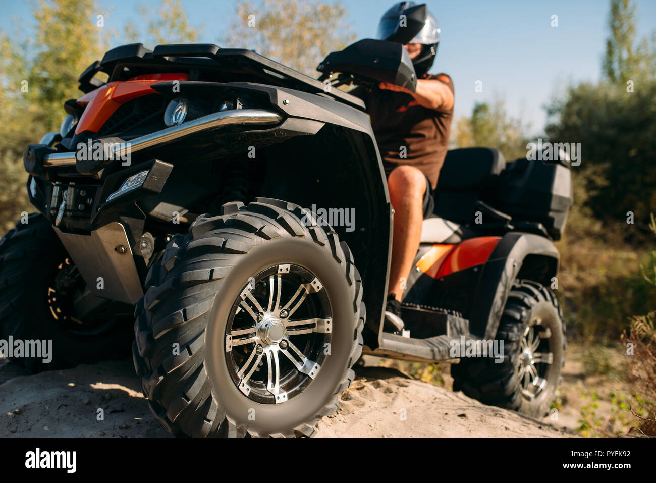 Atv rider climbing the sand mountain in quarry, back view, dust clouds ...