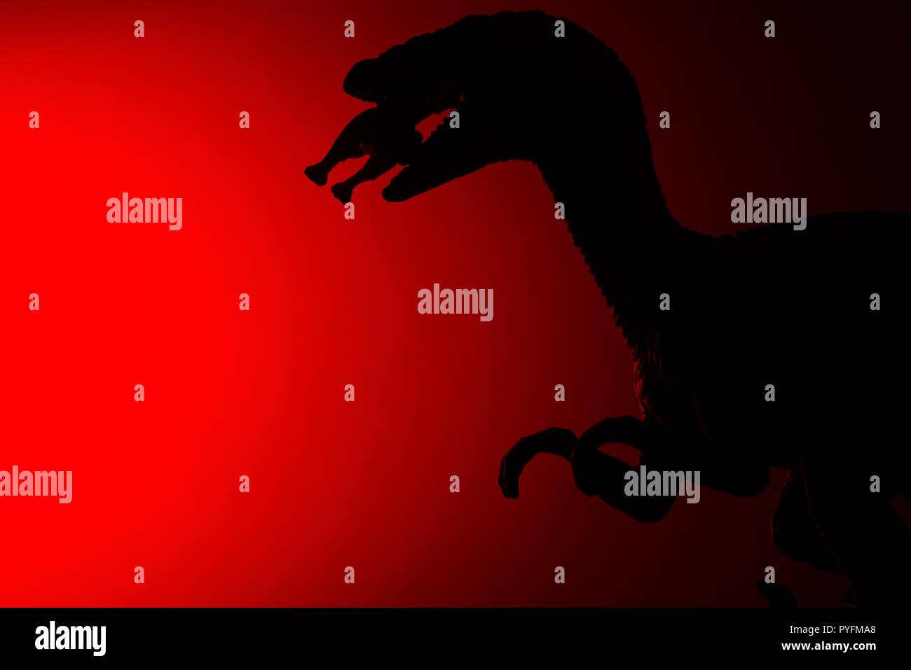 shadow of Deinonychus biting a smaller dinosaur with red light in dark ...