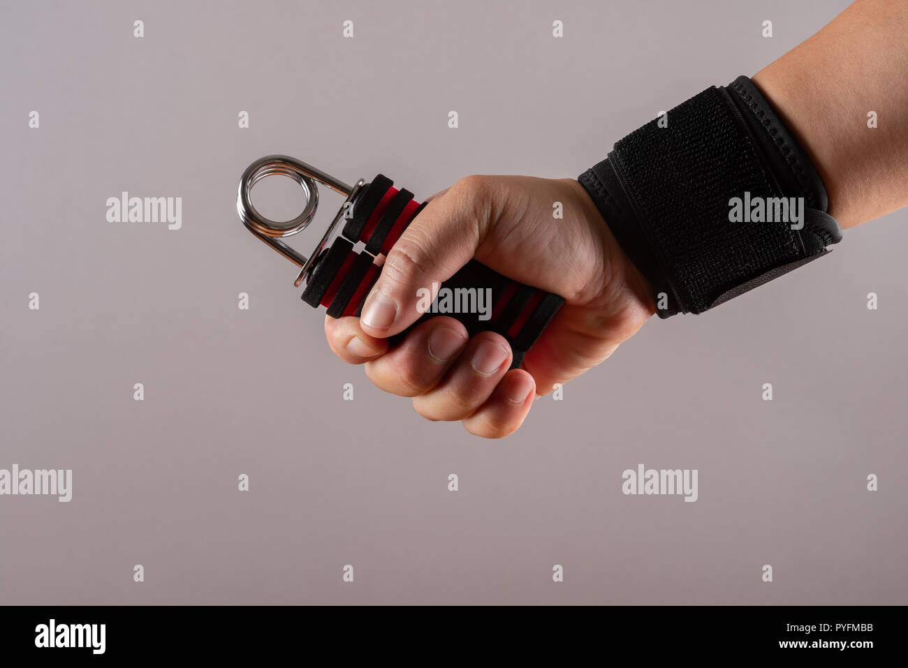 hand with a wrist protective strap doing exercises by squeezing an A