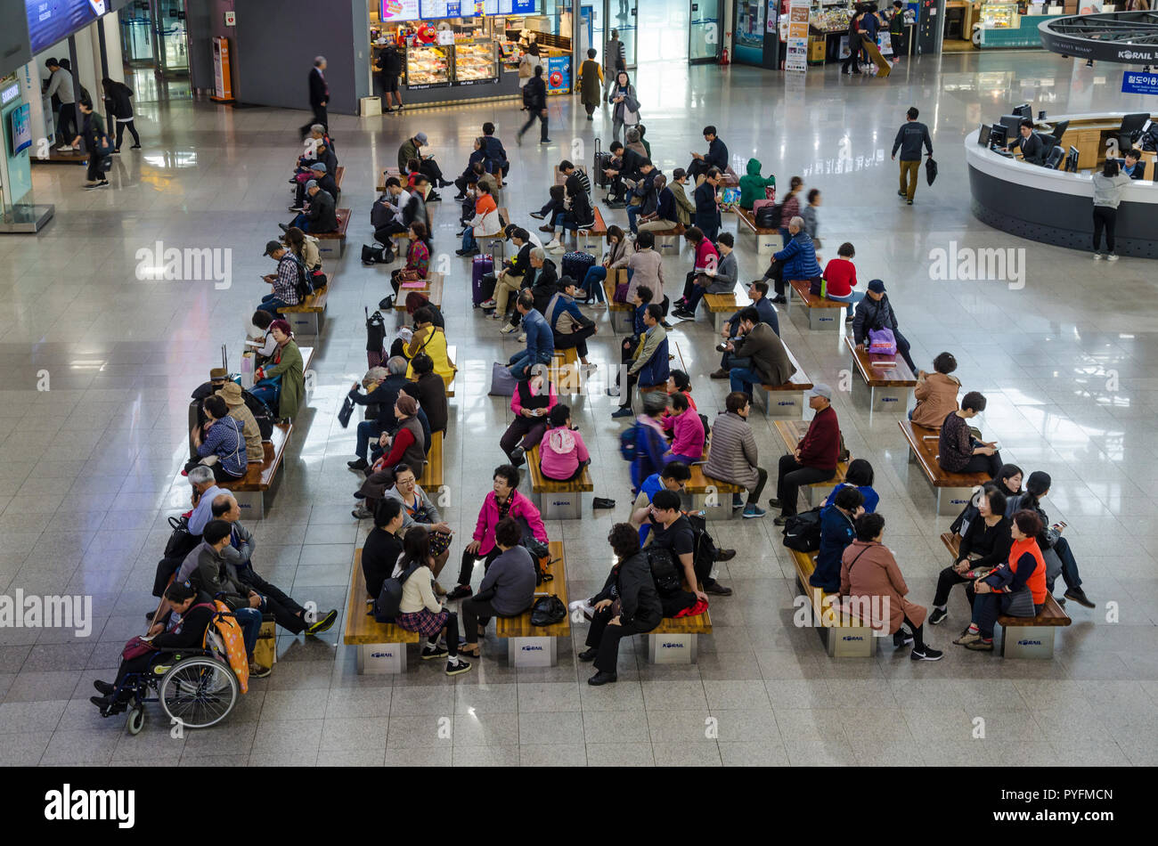 People sitting on benches in the main concourse of Busan Railway Station in South Korea. Stock Photo