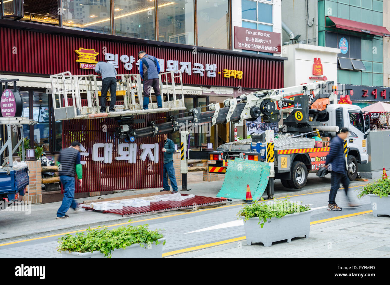 Workmen use a crane to lift into position and fit a new fascia to the
