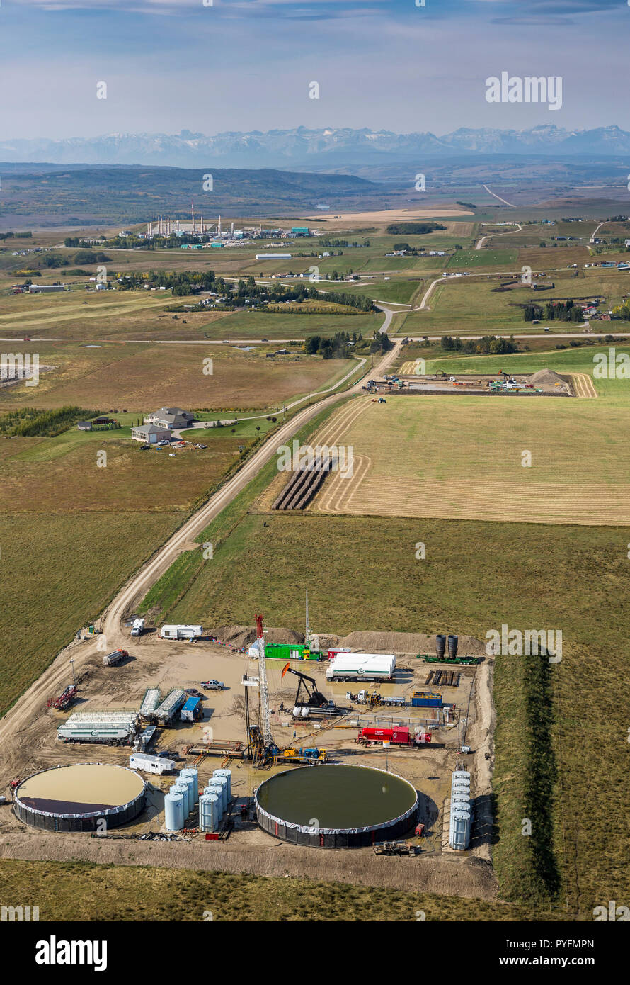 Service rig and operations at lease near Cochrane, Alberta Canada with Rocky Mountains and gas plant in background. Stock Photo