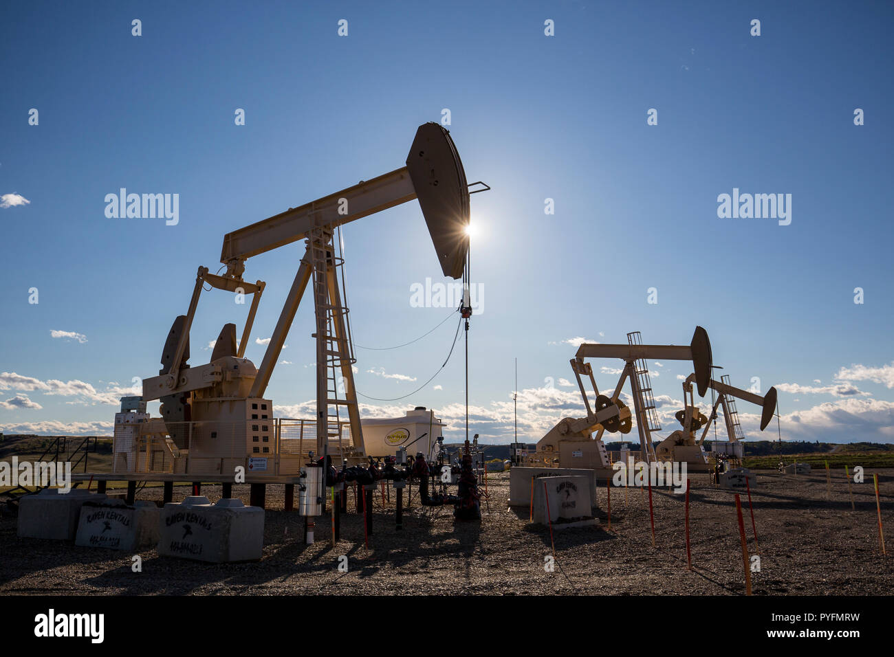 Trio of oil pumpjacks working north of Cochrane, Alberta Canada Stock Photo