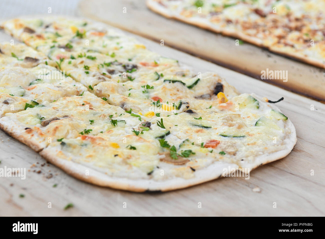 Black Forest speciality called Flammkuchen in south Germany and Tarte flambee in northeast France - vegetarian - on wooden platter Stock Photo