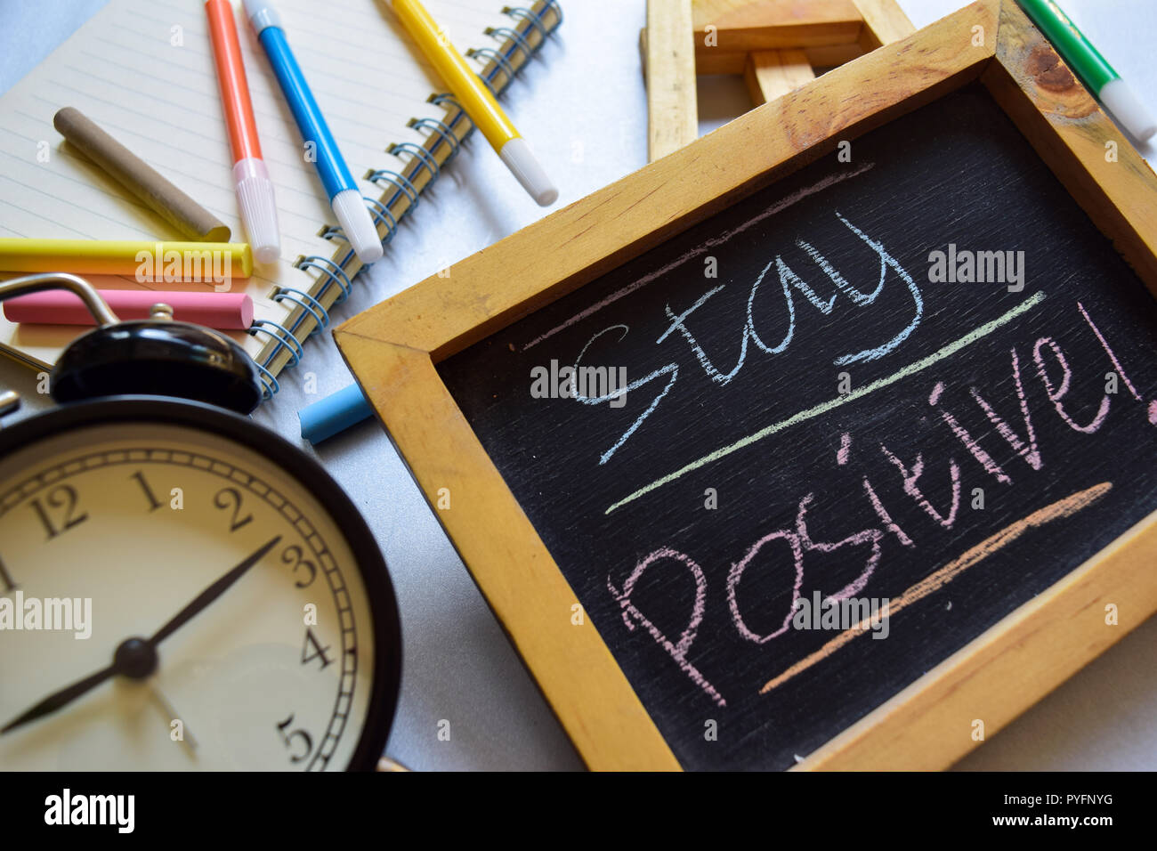 Stay positive on phrase colorful handwritten on chalkboard, alarm clock