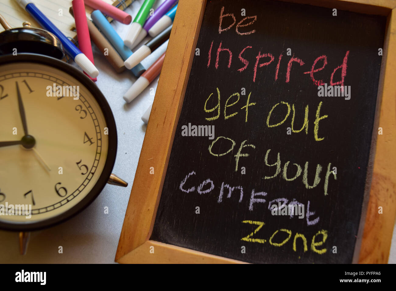 Be inspired get out of your comfort zone on phrase colorful handwritten on chalkboard, alarm clock with motivation and education concepts Stock Photo