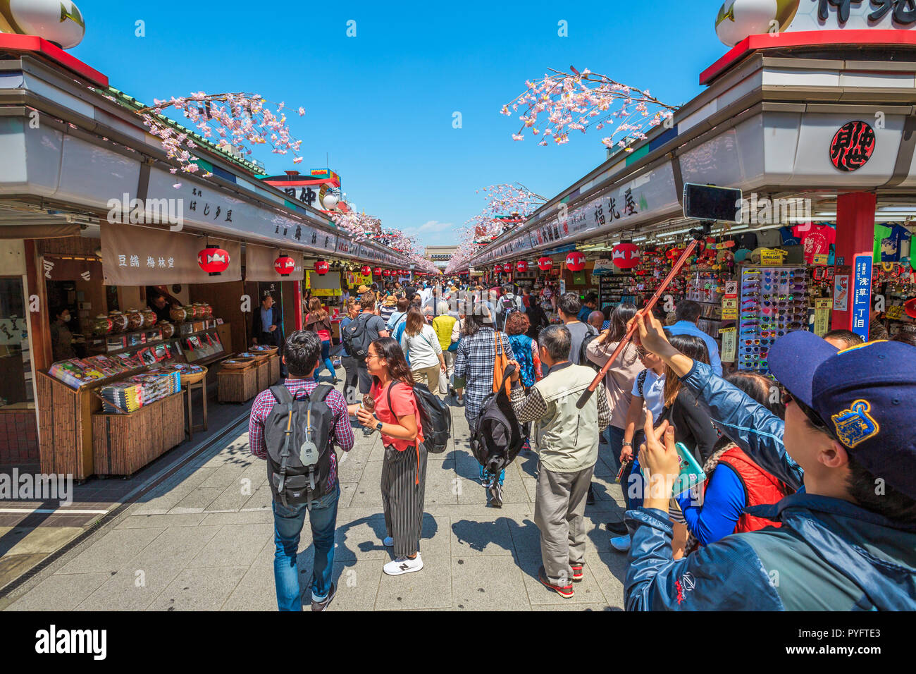 Tokyo, Japan - April 19, 2017: crowd of people in spring sakura on Nakamise Dori, street with food and souvenirs shops, connetting the Kaminarimon Gate at the entrance of Senso-ji Buddhist Temple. Stock Photo
