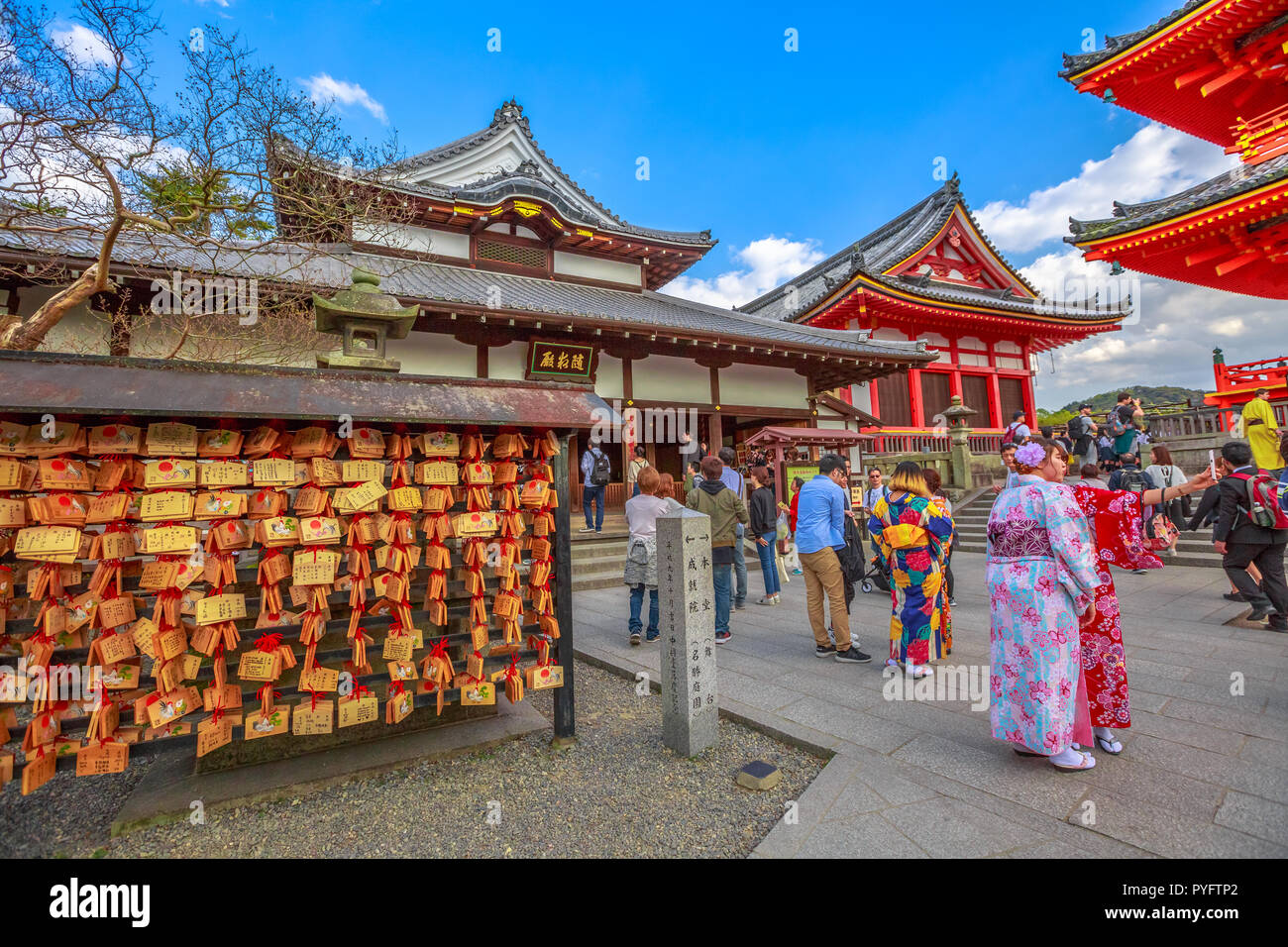 Kyoto, Japan - April 24, 2017: wooden plaques or Ema, bearing people's prayerspeople, women in kimonos takes selfie and red pagoda inside Kiyomizu-dera, one of the most celebrated temples of Japan. Stock Photo