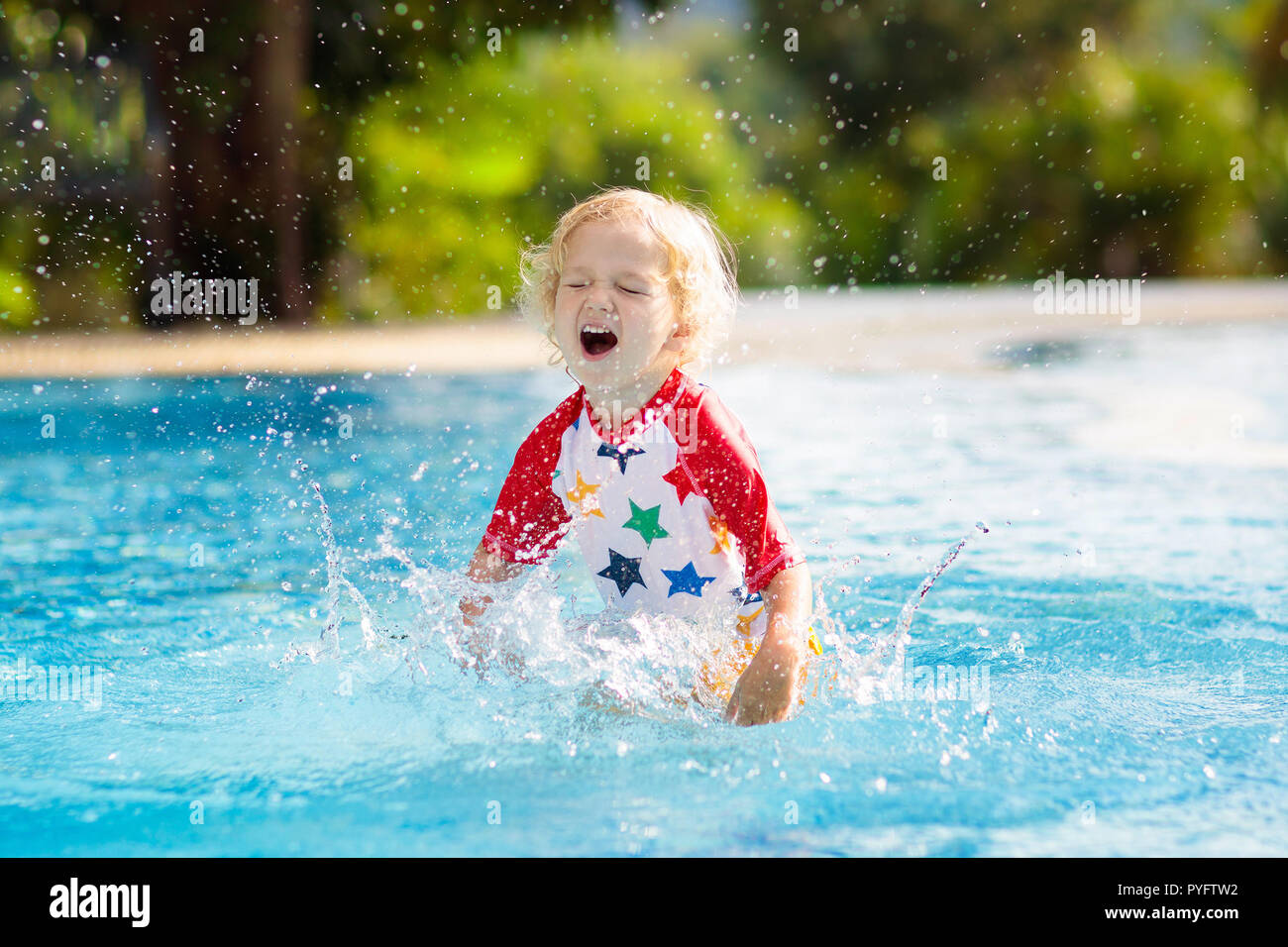 Child playing in swimming pool. Summer vacation with kids. Little boy jumping into water during exotic holiday in tropical island resort. Children swi Stock Photo