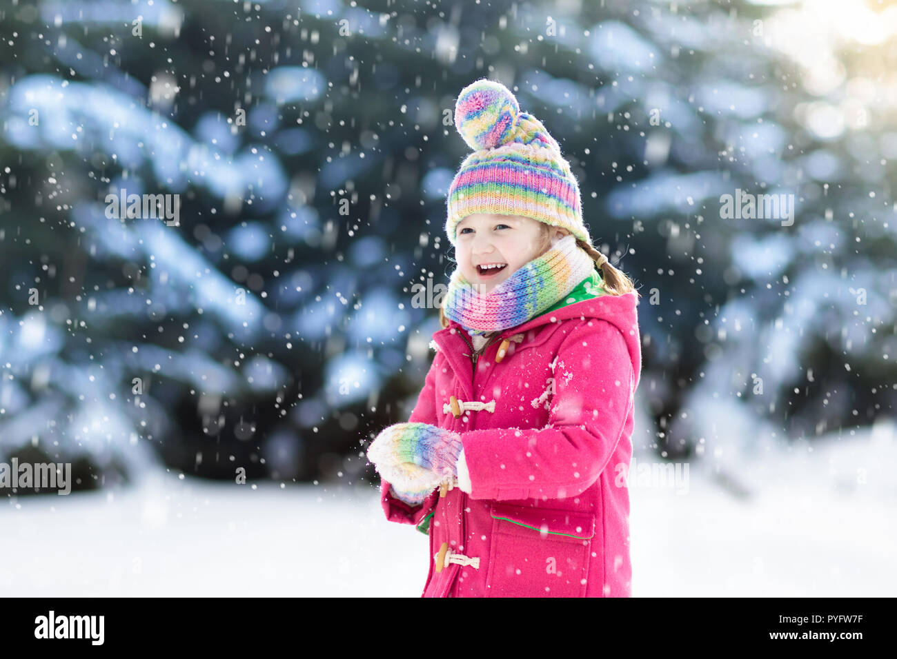 Child playing with snow in winter. Little girl in colorful jacket and ...