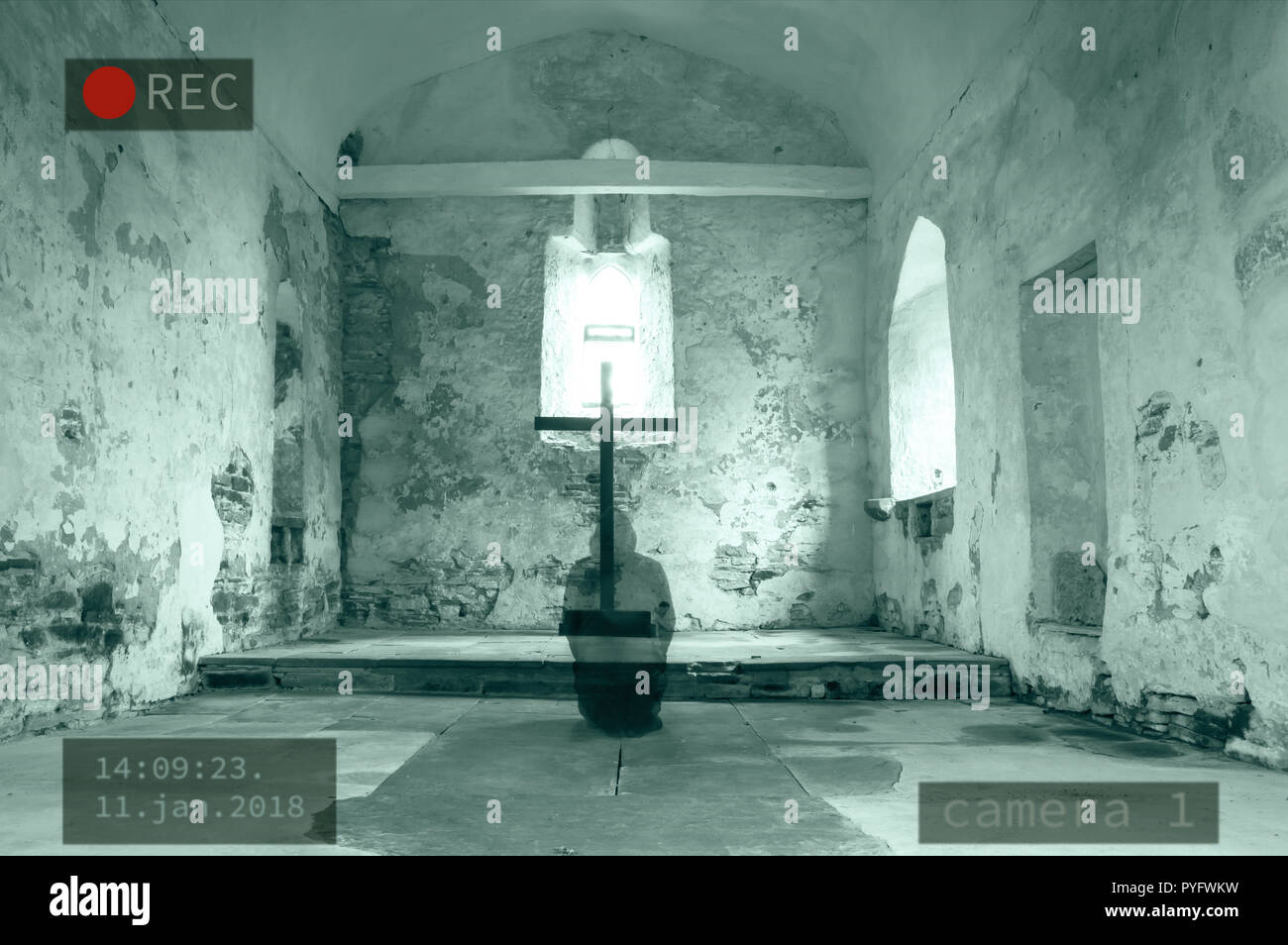 A hooded ghost kneeling next to a cross in a disused church. With a photoshopped edit of a security camera. Stock Photo