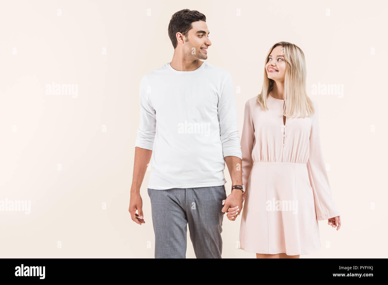 happy young couple holding hands and smiling each other isolated on ...