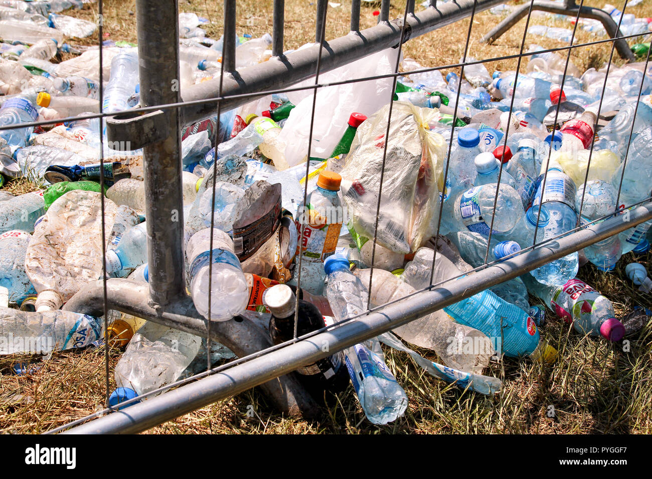Belgrade, Serbia - June 25, 2017: Plastic bottles tossed by the metal fence. Used empty pet bottles thrown away and left on grass after an open air. Stock Photo