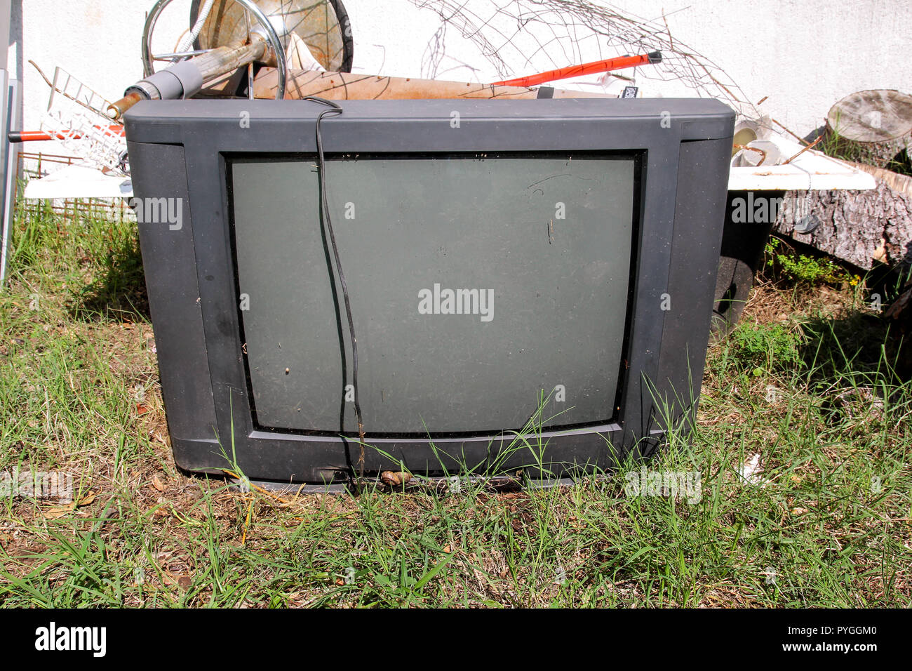 Old TV set dumped and left in the garden along with other bulky trash