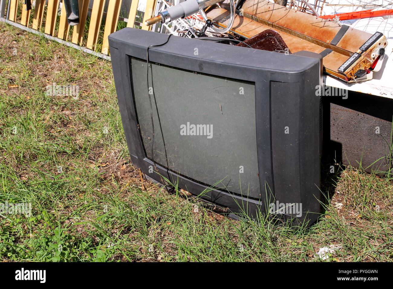 Old TV set dumped and left in the garden along with other bulky trash