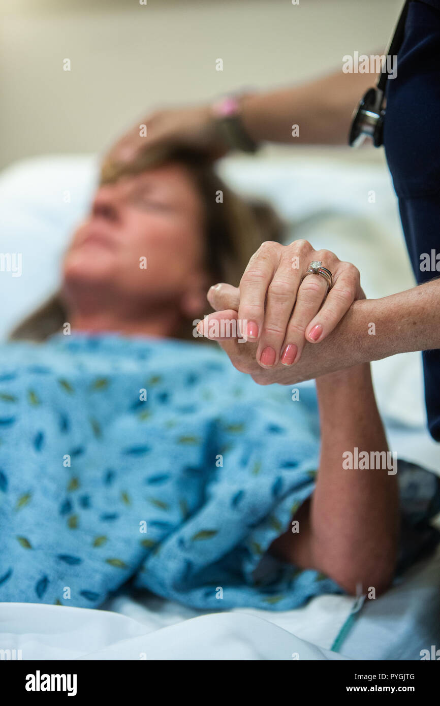Doctor and a nurse care for a patient in a hospice hospital as the patient nears end-of-life care. Stock Photo