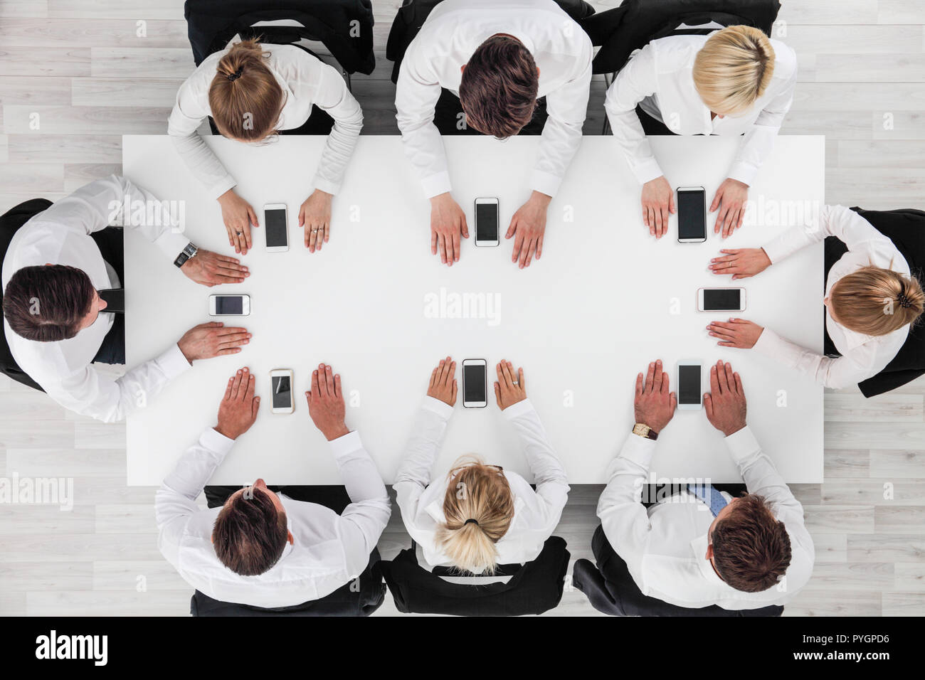Business people not using smartphones sitting around white table Stock Photo