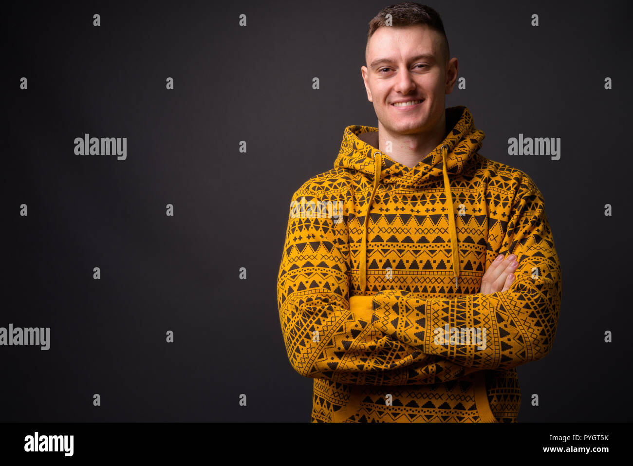Happy young handsome man wearing hoodie with arms crossed Stock Photo