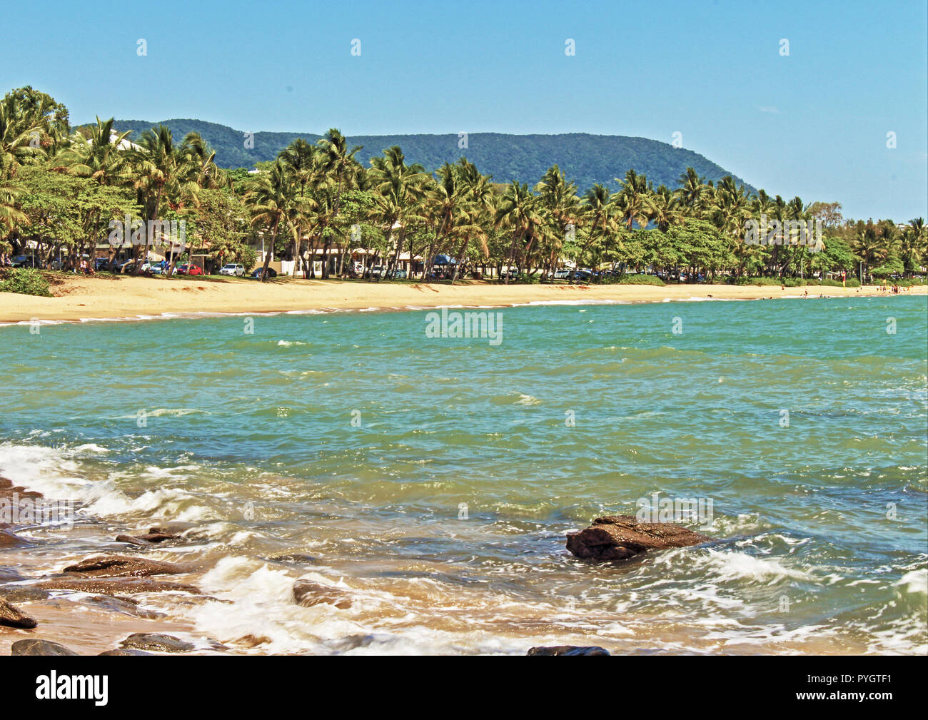 The beautiful palm tree lined beach and esplanade as seen from across the cove at Trinity Beach, a northern beach suburb Cairns QLD Australia Stock Photo