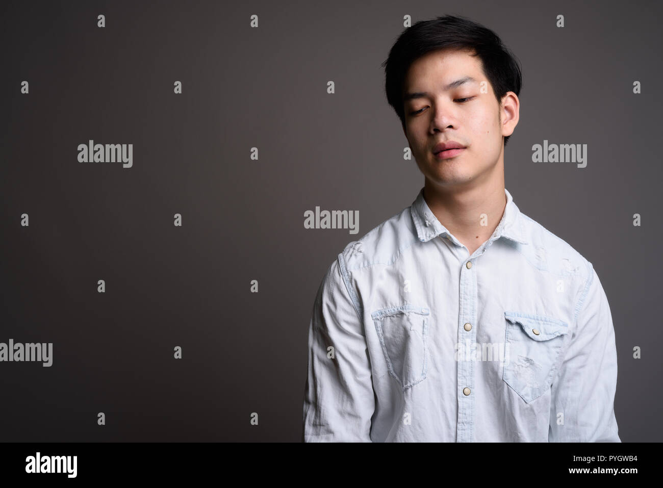 Portrait of young Asian businessman with eyes closed Stock Photo