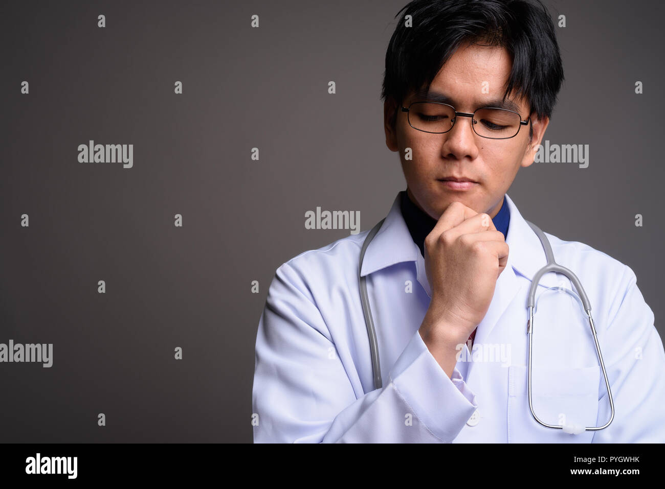 Face of young serious Asian man doctor thinking Stock Photo