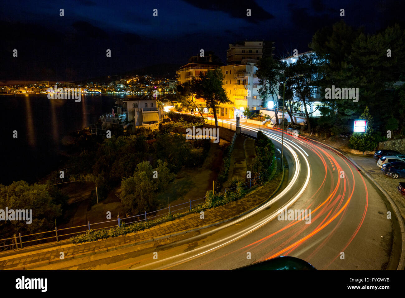 Long exposure night landscape photo, cityscape at the beautiful sea town of Saranda, Albania with star effect of the city lights and sea water reflections Stock Photo