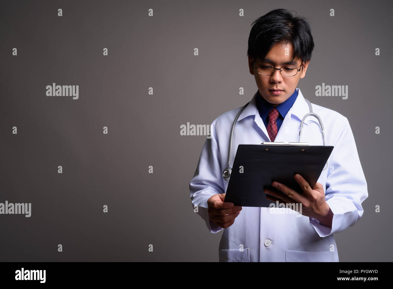 Portrait of young Asian man doctor reading checklist from clipboard Stock Photo