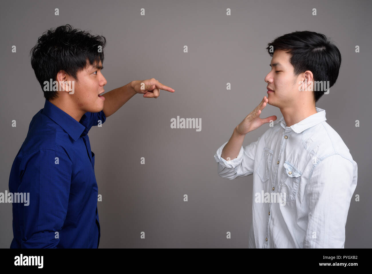 Two young handsome Asian men having argument Stock Photo