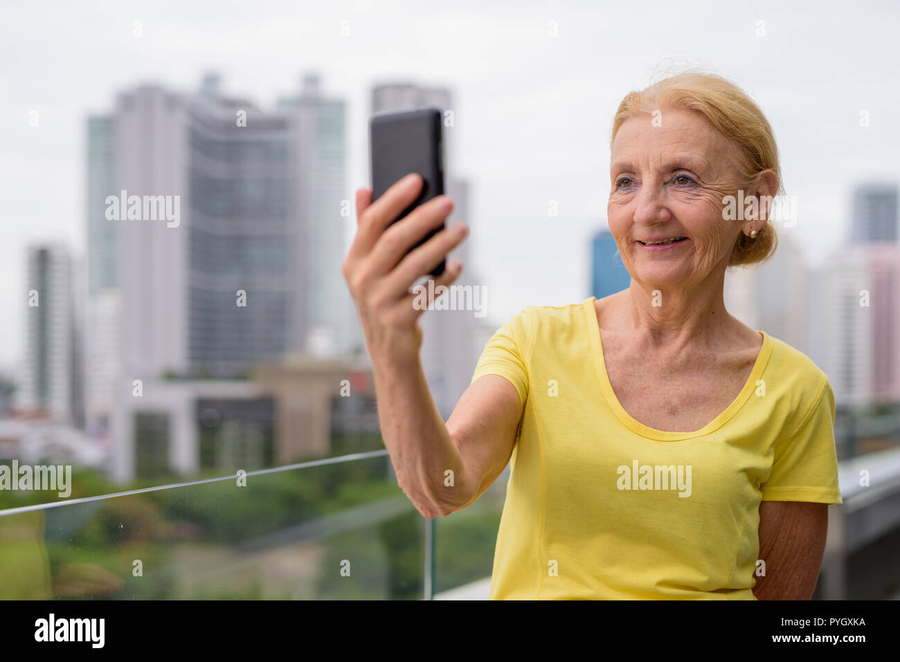 Beautiful senior woman using mobile phone in city Stock Photo