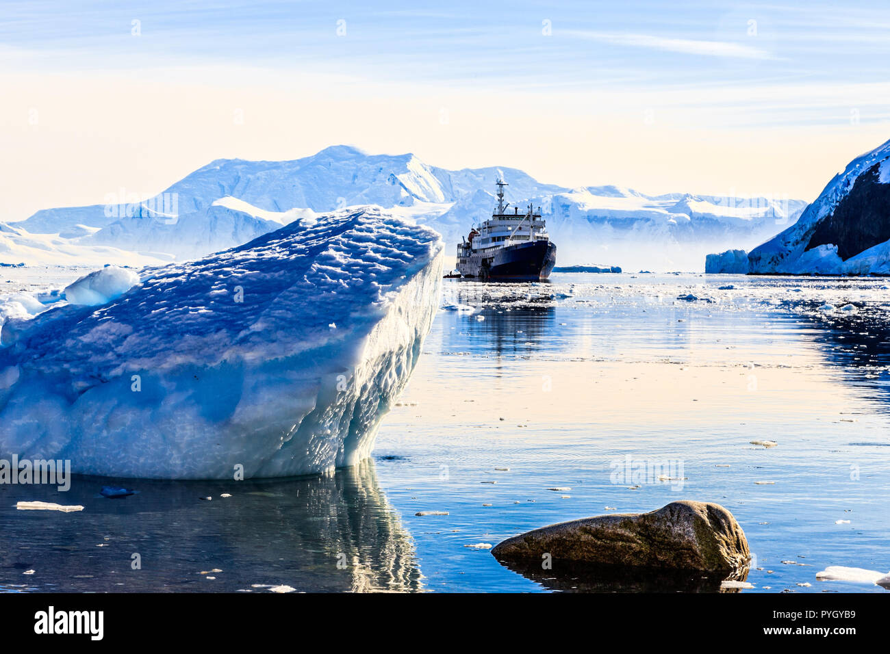 Touristic antarctic cruise ship among the icebergs with glacier in background, Neco bay, Antarctica Stock Photo