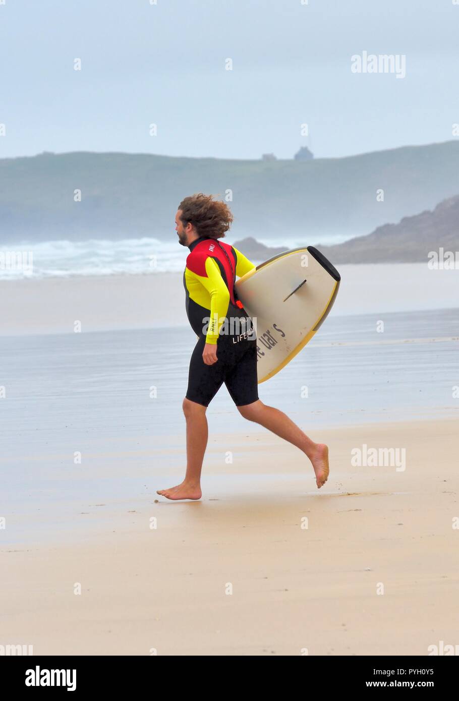 RNLI Lifeguard running towards the sea to make a rescue,Perranporth,Cornwall,England,UK Stock Photo