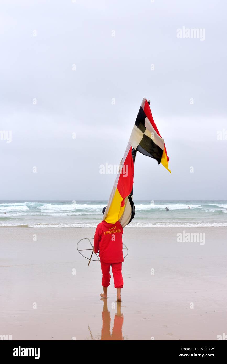 RNLI Lifeguard carrying safety warning flags Stock Photo
