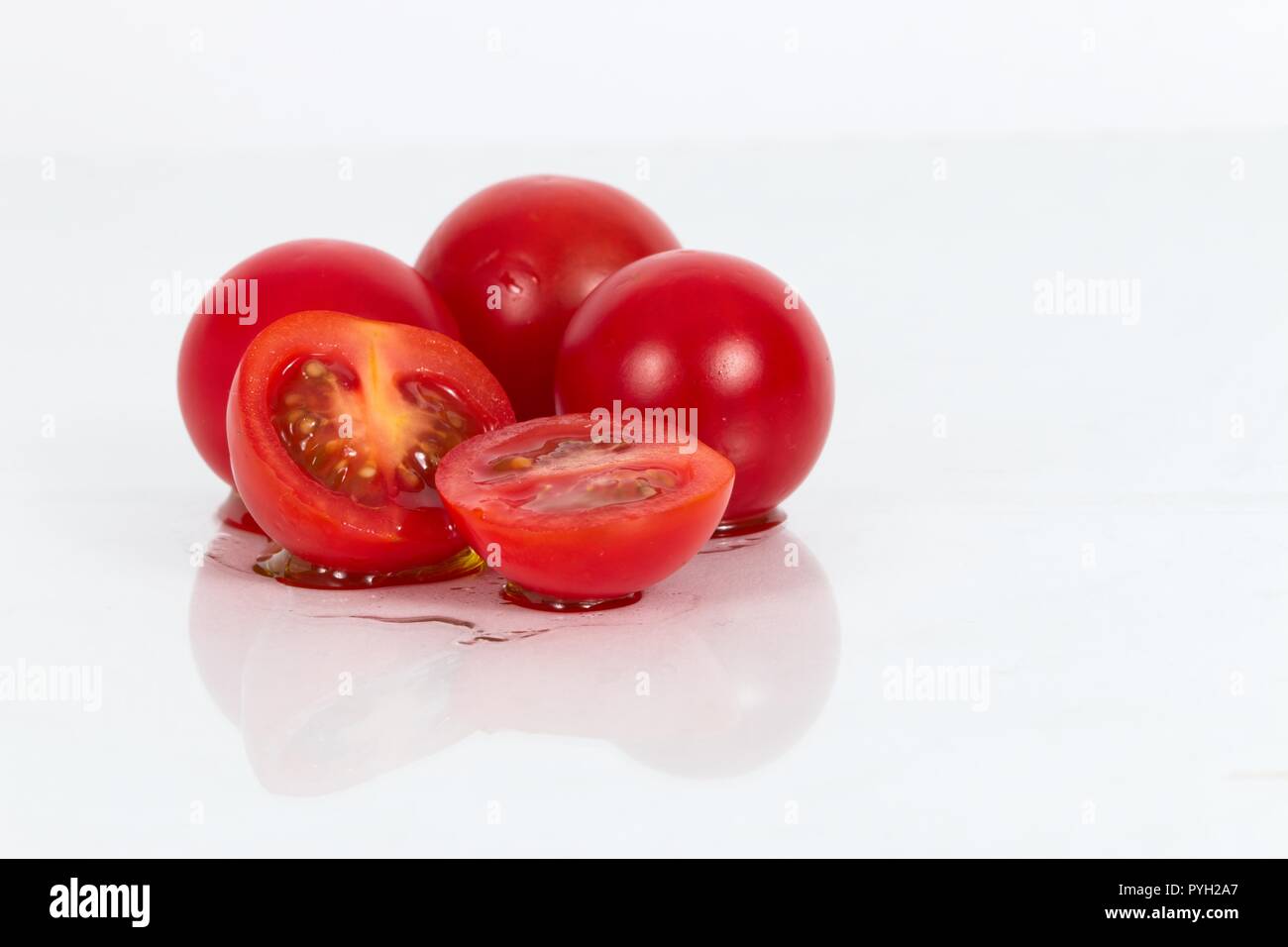 Cherry Tomatoes against a white background. One sliced cheery tomato Stock Photo