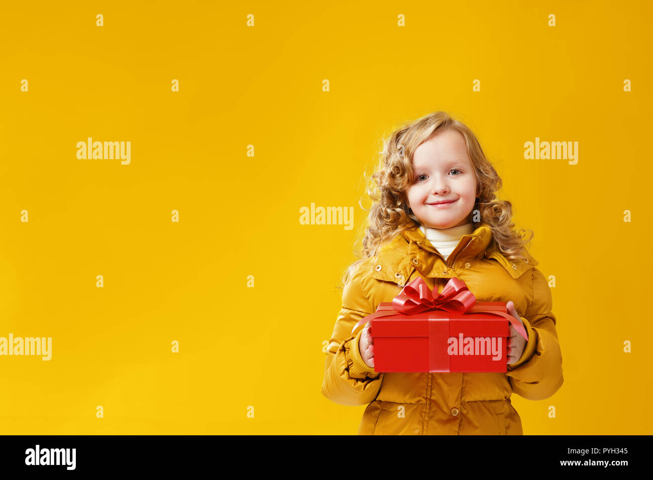 Happy little girl preschooler in a winter jacket is holding a box with