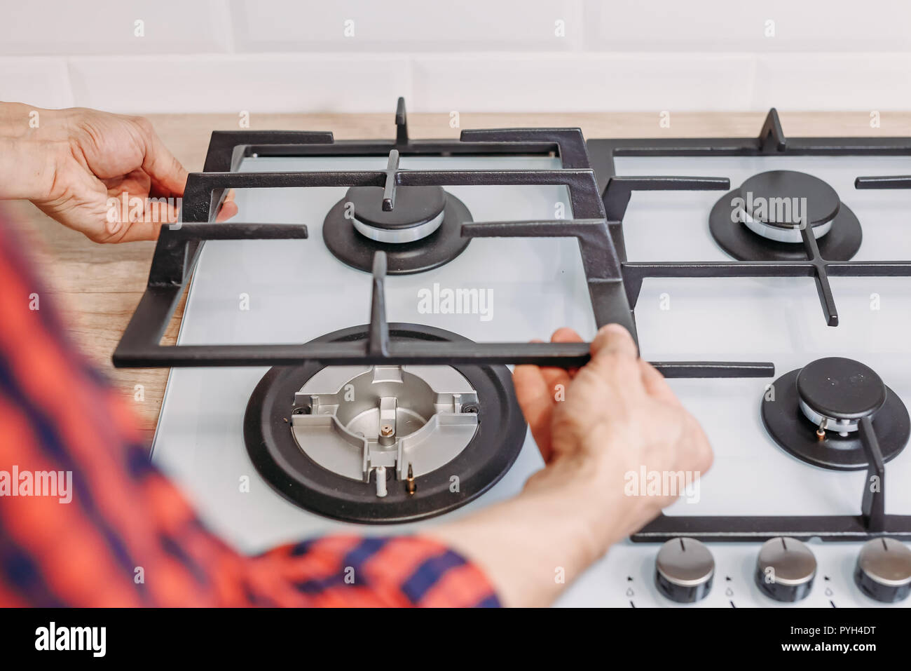 Man hand install burner ongas hob in kithen, close up. Repairs of gas control panel Stock Photo