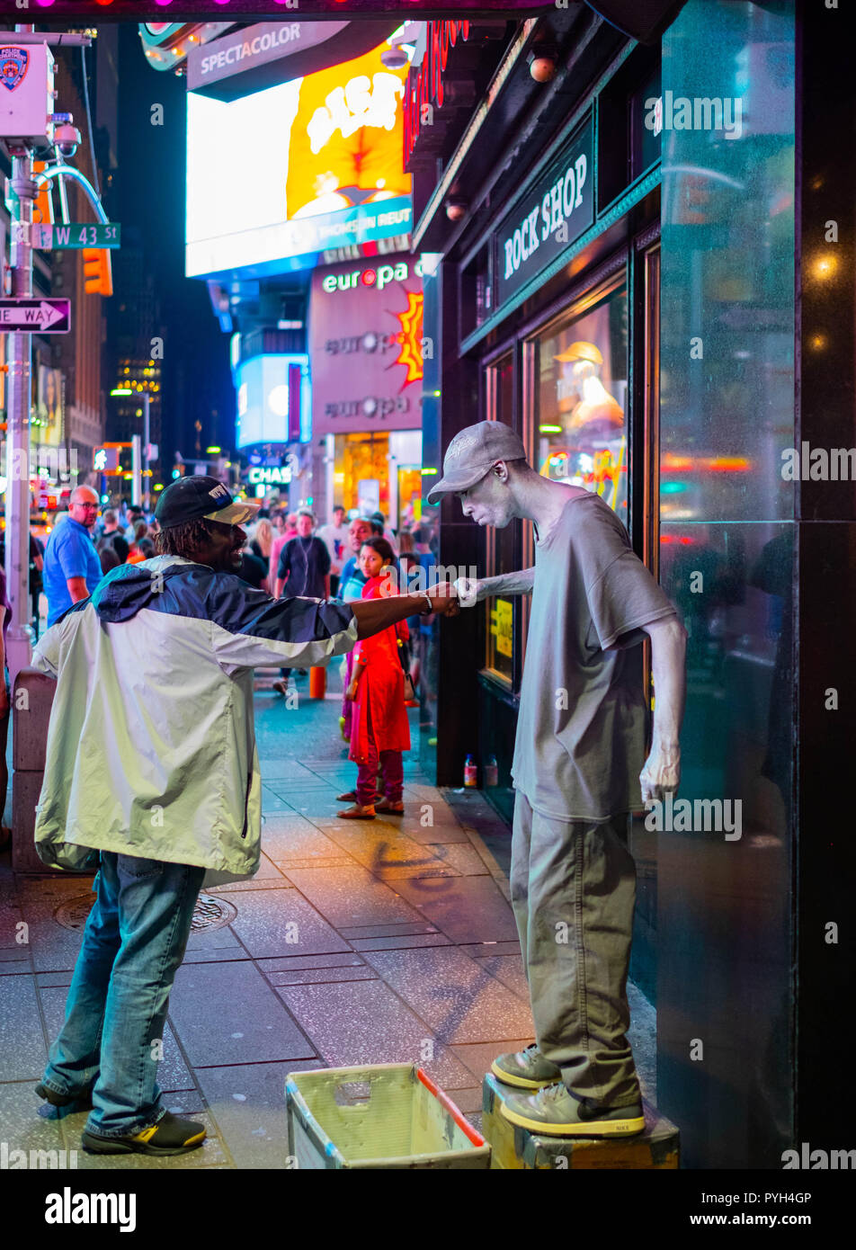 A local man fist pumps a street performer in Times Square, Midtown, Manhattan, on a busy night in front of the neon lights Stock Photo