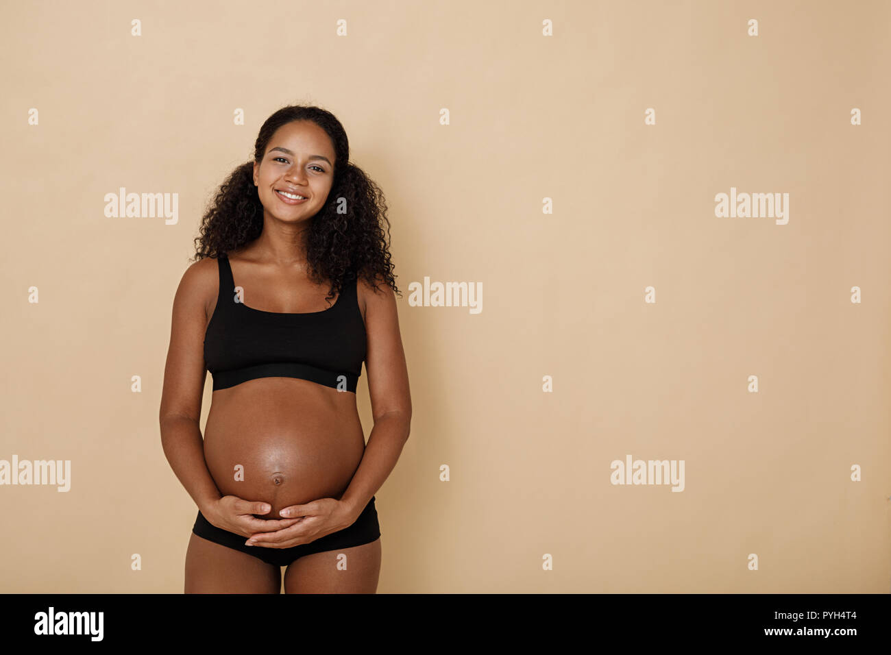 Studio portrait of pregnant woman holding her belly Stock Photo