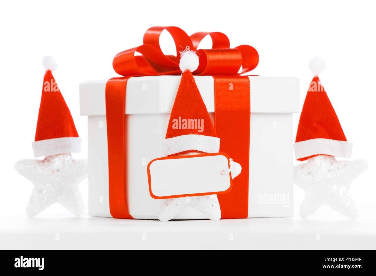 White gift box with red ribbon, stars with santa claus hats isolated on ...