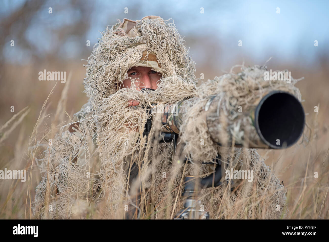 Camouflage wildlife photographer in the ghillie suit working in the wild Stock Photo
