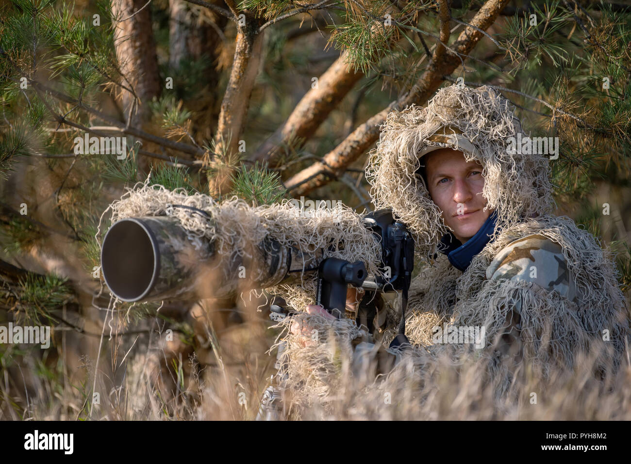 Camouflage wildlife photographer in the ghillie suit working in the wild Stock Photo