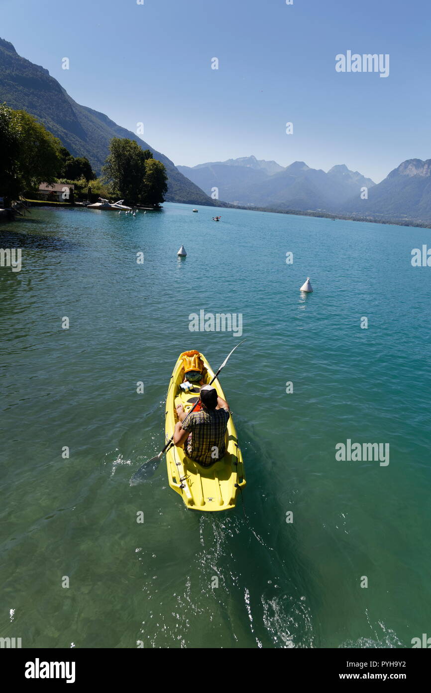 Close up of a rower on a yellow canoe on turquoise water on Lake Annecy France Stock Photo