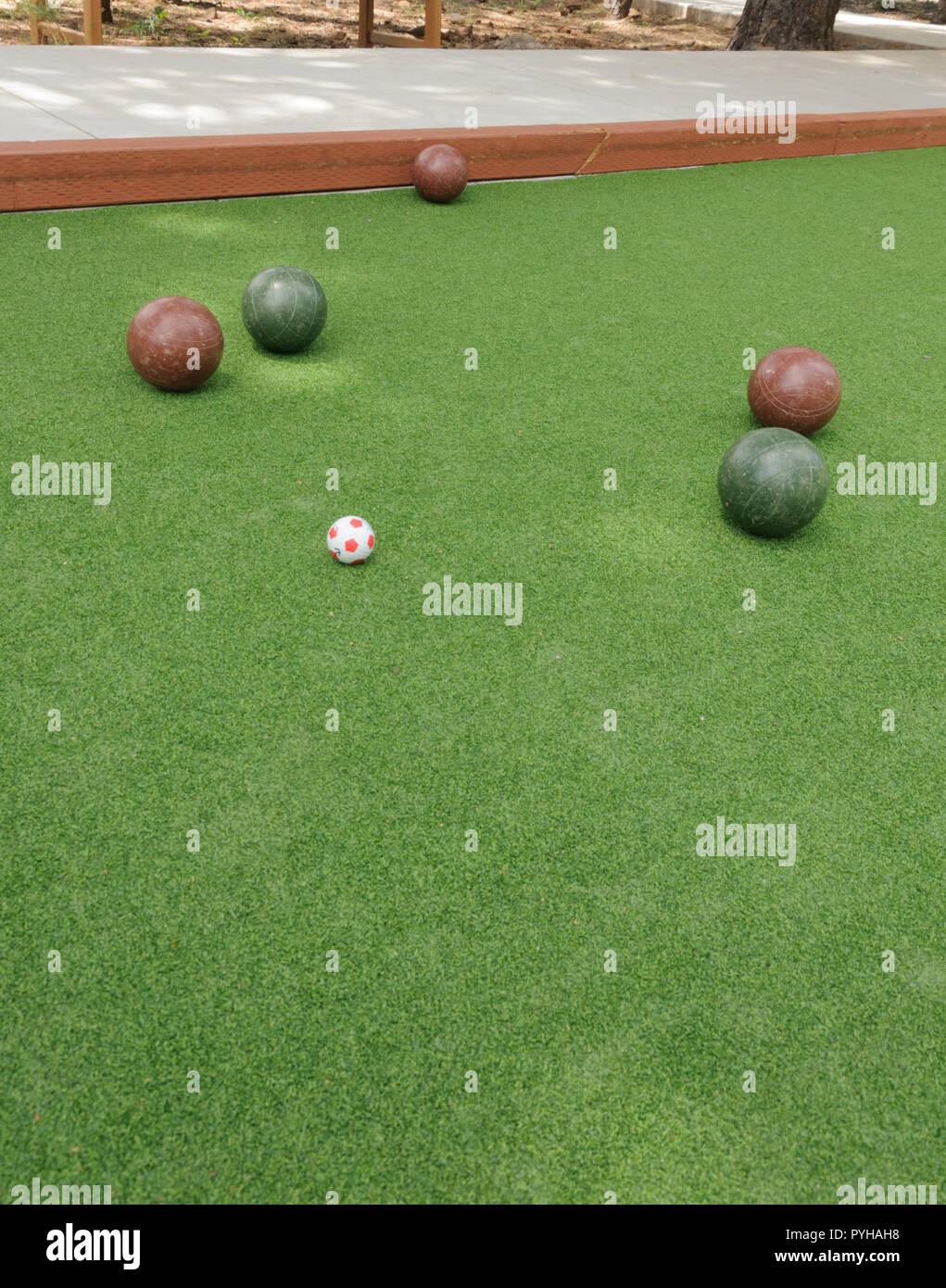 Bocce Balls, 3 red balls and 2 green balls surround the polina on a