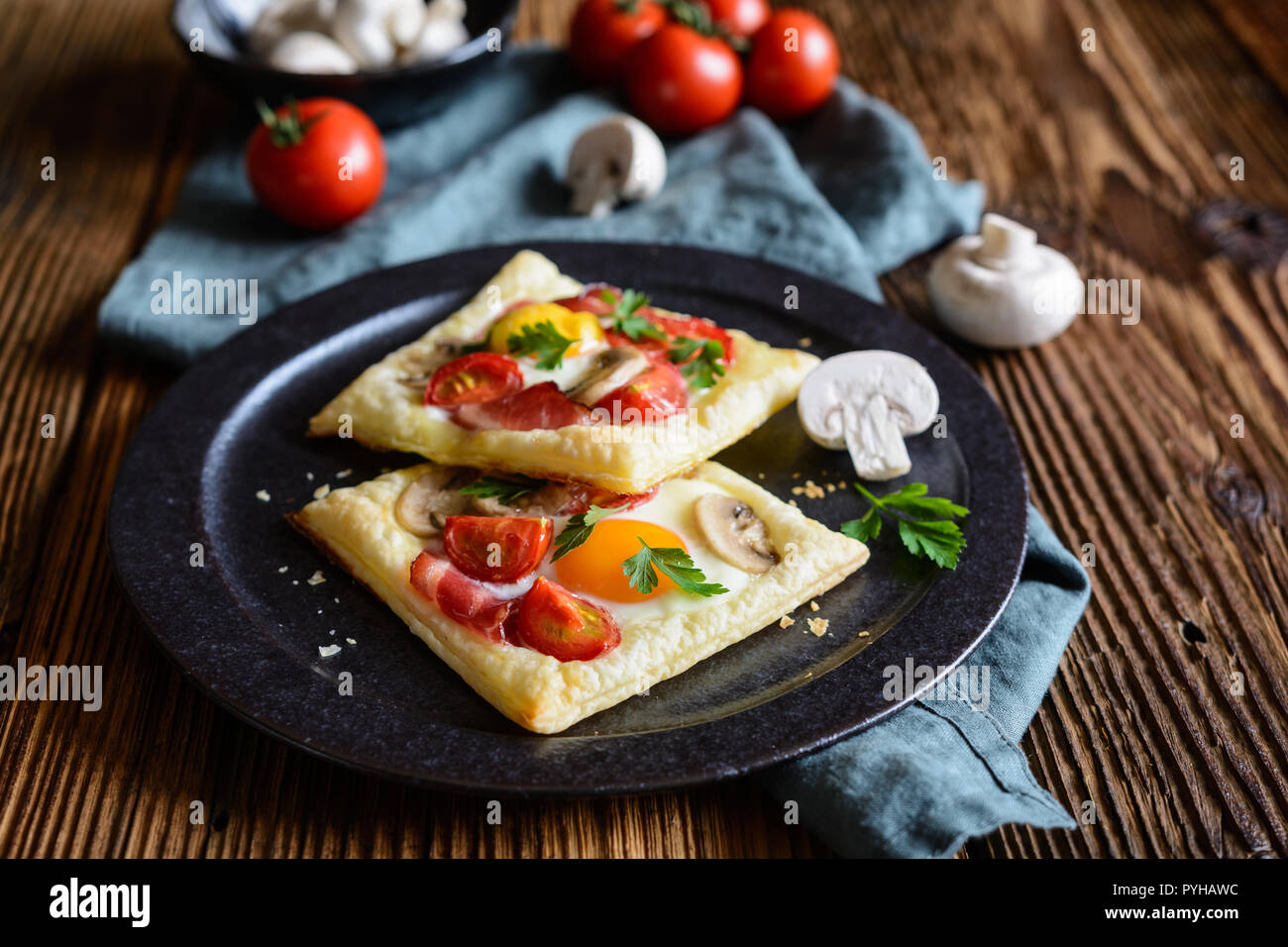 Savory puff pastry pies with egg, bacon, mushrooms and tomato Stock