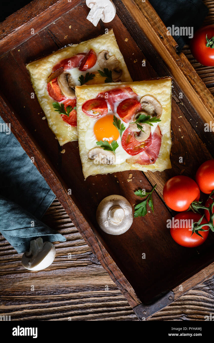 Savory puff pastry pies with egg, bacon, mushrooms and tomato Stock