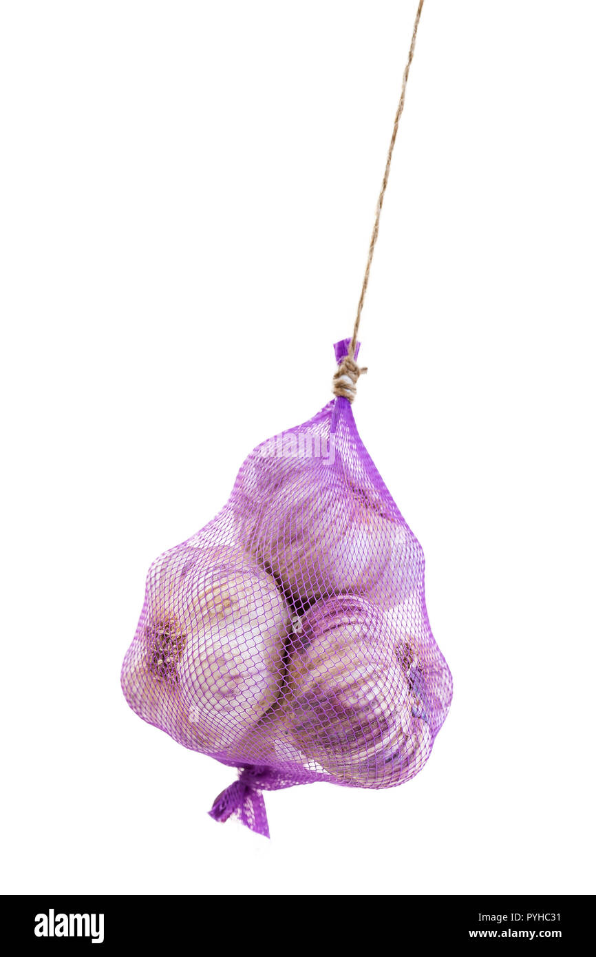 pink garlic hanging packed in a purple net bag on white background Stock Photo