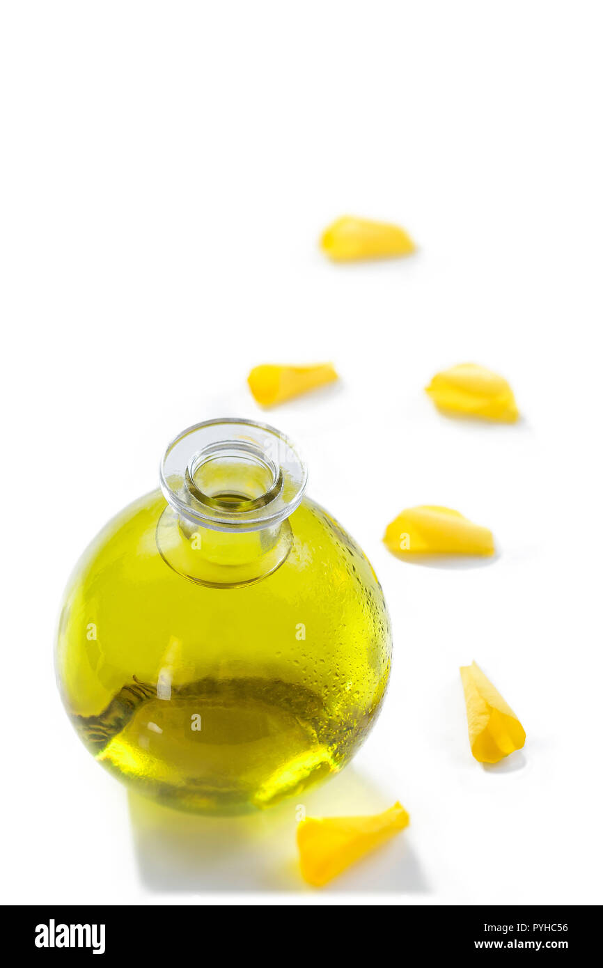 A bottle of rose essential oil with yellow rose petals on a white background Stock Photo