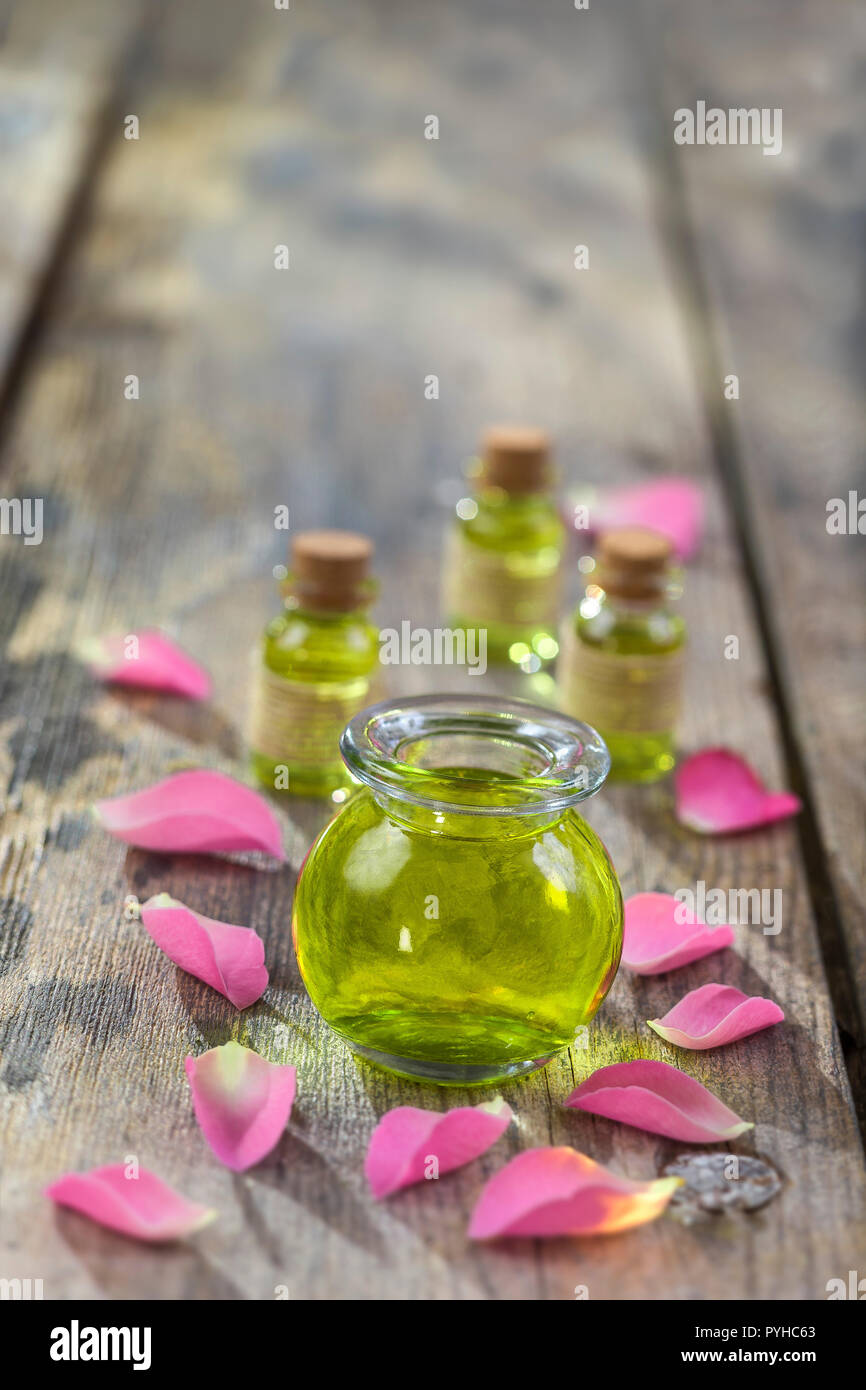 Rose flower petals with aromatherapy essential oil glass bottle isolated over wooden, background, copy-space Stock Photo